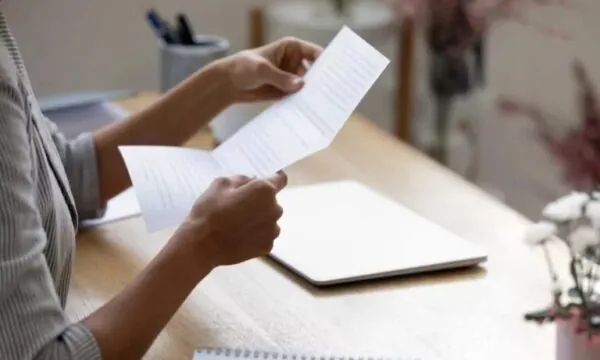 Woman's hands holding up a typed letter of recommendation for college.