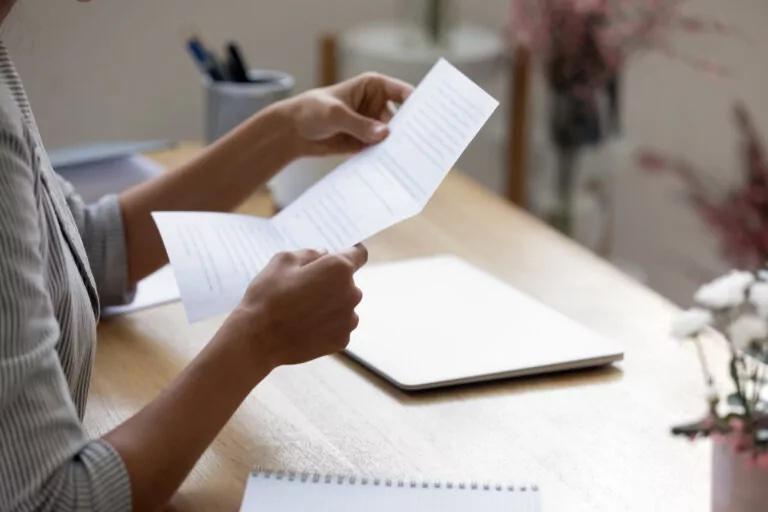 Woman's hands holding up a typed letter of recommendation for college.