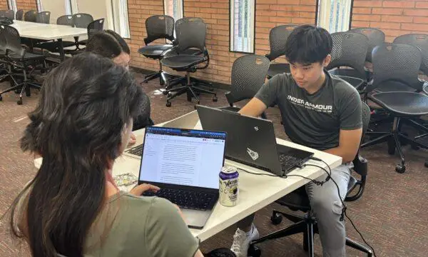 Two students in a USC Summer Programs course study at their laptops in a classroom with brick walls. Here's how to succeed as a first-generation college student.