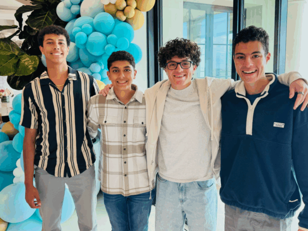 Augustine Awadalla poses with Halos Snacks co-founders Isaac Abraham, Joshua Abraham and Matthew Awadalla, with balloons in the background.