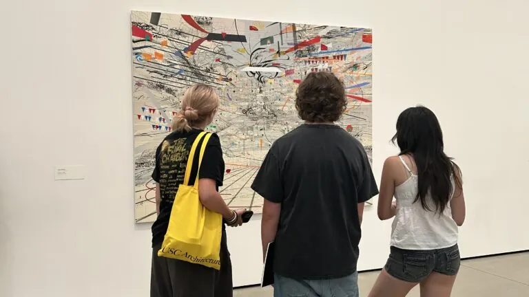 Three high school students in USC Summer Programs pause to look at a piece of abstract artwork at The Broad museum, with their backs facing the viewer.