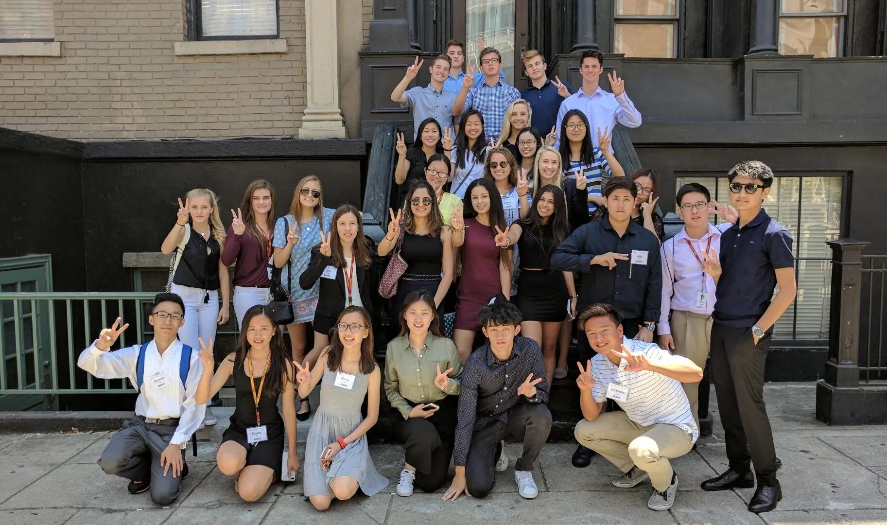 A group of students poses together on outdoor steps, smiling and holding up the USC "Fight On" hand sign.