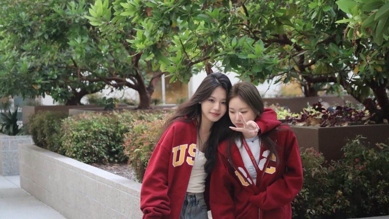 wo students wearing USC sweatshirts smiling and posing together outdoors.