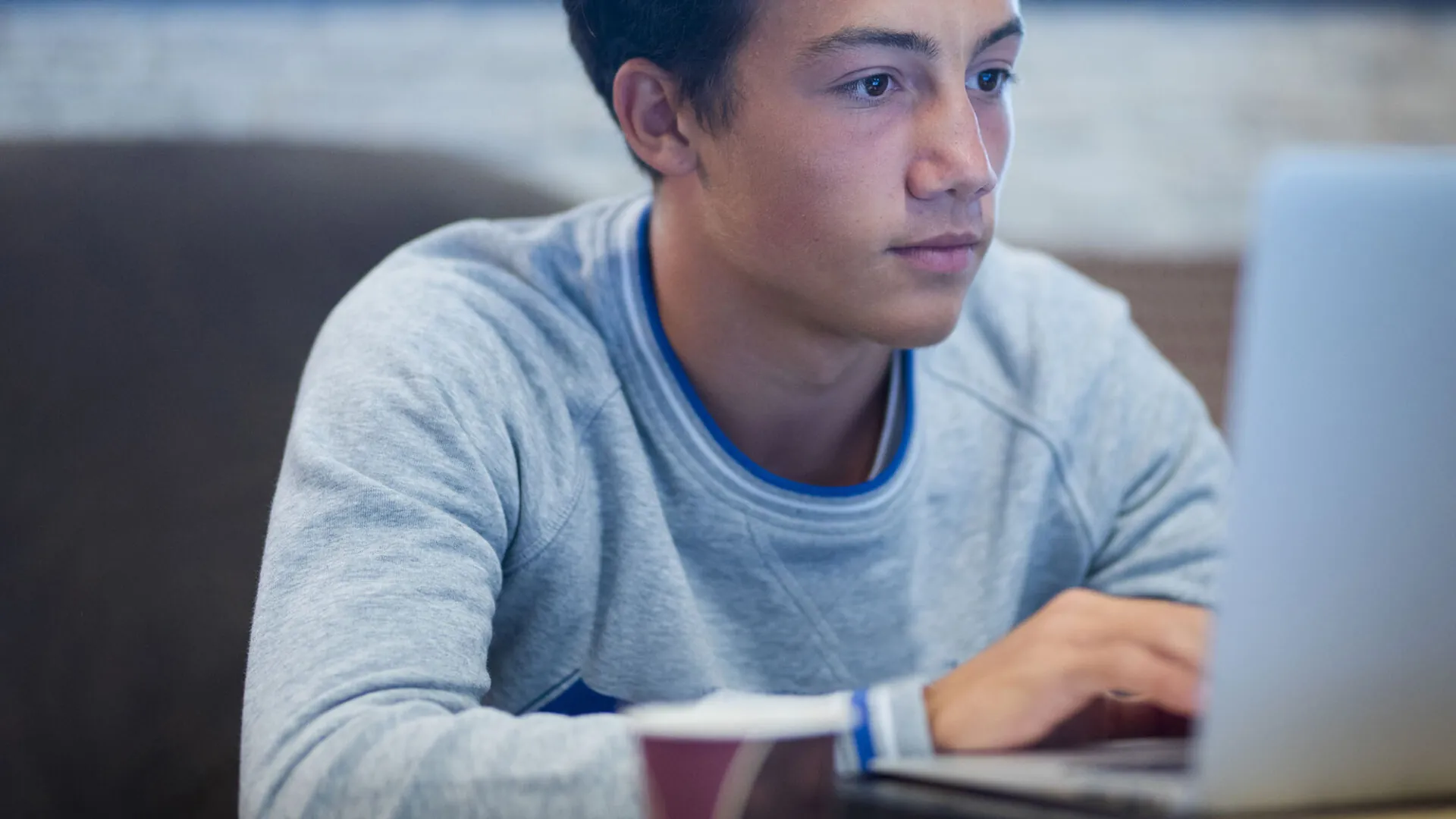 Focused student working on a laptop with a coffee cup nearby, representing USC Pre-College online course “Finance: From Personal Literacy to Global Markets,” where learners study at their own pace and earn a Certificate of Completion.