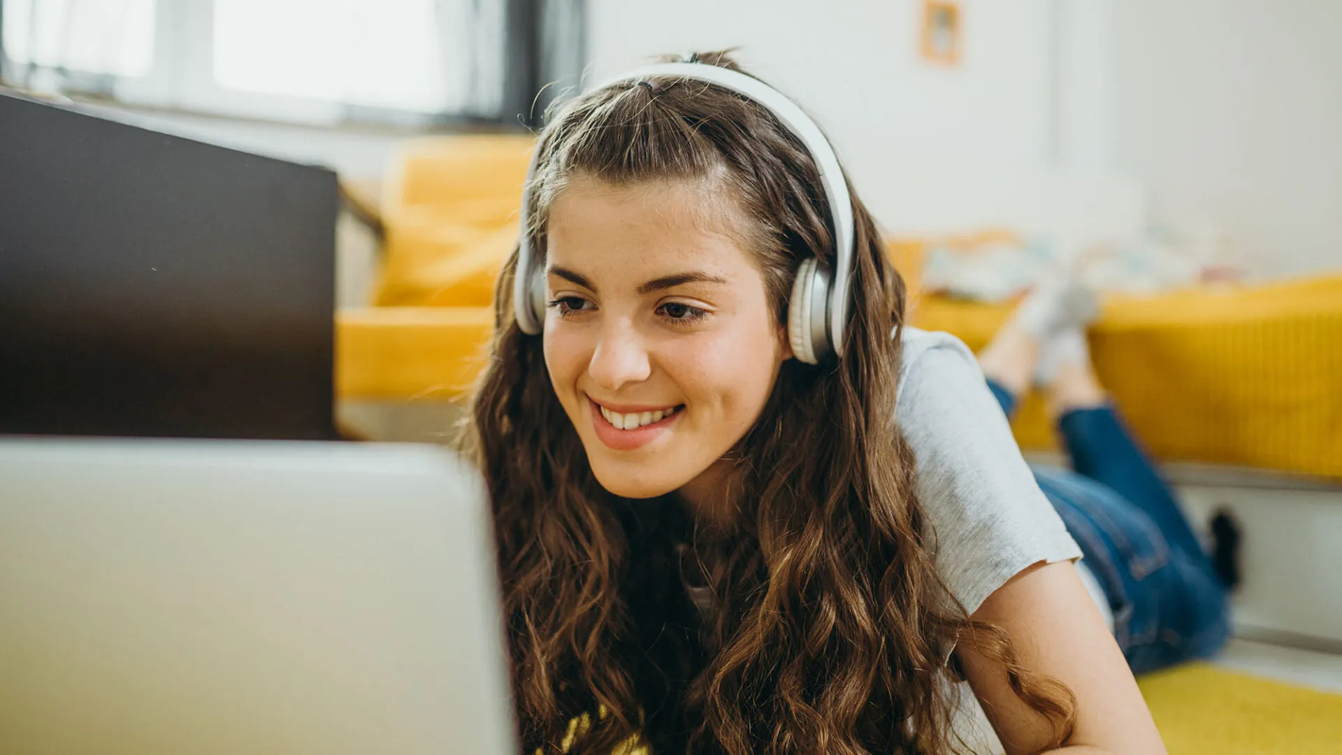Smiling student wearing headphones and studying on a laptop at home, representing USC Pre-College online course “Digital Marketing: From Content Creation to Strategic Planning,” where students learn flexibly and earn a Certificate of Completion.